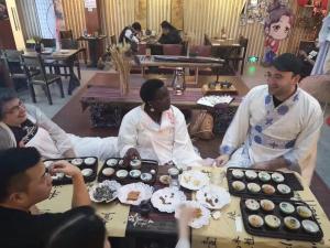 Un groupe de personnes assises autour d'une table avec des petits gâteaux dans l'établissement Onederz Hostel Hangzhou, à Hangzhou