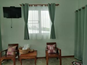 a living room with two chairs and a window at บ้านย่า ณ ท่าไทร in Si Racha