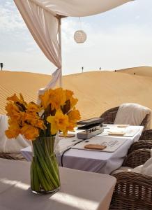 Eine Vase gelber Blumen auf einem Tisch in der Wüste. in der Unterkunft STARLIGHT CAMP in Dubai