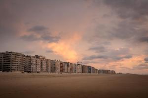 a row of buildings on the beach at sunset at Gezellig app in de Belle Époque wijk van Oostende in Ostend