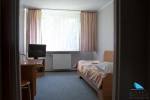 a hotel room with a bed and a desk and a window at Na Skarpie in Olsztyn