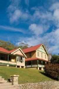 a large house with a red roof on a yard at Yarrangobilly Caves House in Yarrangobilly