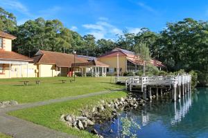 un edificio con muelle junto a una masa de agua en Huskisson Holiday Motel Cabins, en Huskisson