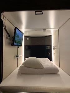 - une chambre avec un lit et une télévision murale dans l'établissement Matsue Urban Hotel CubicRoom, à Matsue