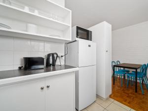 a kitchen with white cabinets and a table with blue chairs at Pronto Apartments in Perth