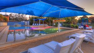 a pool with chairs and a playground with a blue umbrella at Nambucca River Village by Lincoln Place in Macksville
