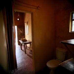a bathroom with a toilet and a table at Tree House Cottage, Ocean View in Praia do Tofo