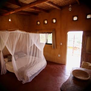 a bedroom with a bed with a mosquito net at Tree House Cottage, Ocean View in Praia do Tofo