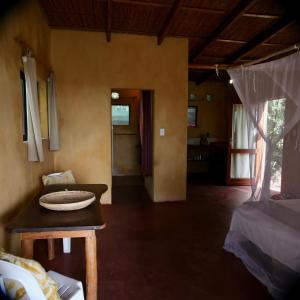 a living room with a table and a room with a bed at Tree House Cottage, Ocean View in Praia do Tofo