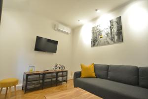 uma sala de estar com um sofá e uma televisão na parede em Apartman LENA em Dakovo