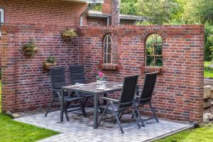 a table and chairs in front of a brick wall at Zur alten Post I in Dagebüll