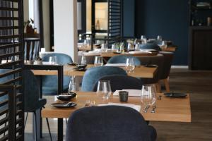 un restaurante con mesas de madera y sillas con copas de vino en Boutique Hotel Texel, en De Cocksdorp