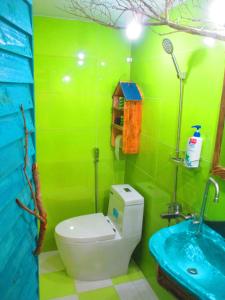 a green bathroom with a toilet and a sink at Phu Nam House - Resort in Phú Quốc