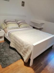 a bedroom with a white bed with a rug at Chambres d'Hôtes Chez Marilou in Aulnay-sous-Bois