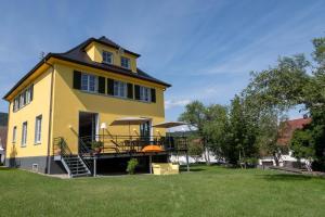 a yellow house with a porch and a lawn at Ferienhaus alte Kinderschule in Hausen am Tann