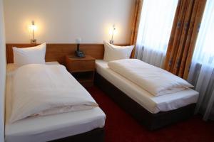 two beds in a hotel room with white sheets at Hotel Accolo in Feldkirchen