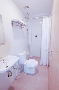 a white bathroom with a toilet and a sink at Maleosan Inn Manado Hotel in Manado