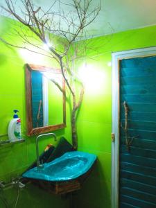 un baño verde con lavabo y un árbol en la pared en Phu Nam House - Resort en Phu Quoc