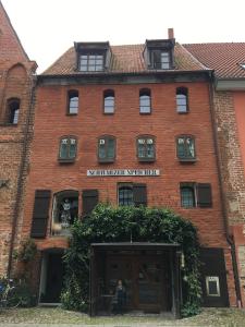 a red brick building with a woman sitting in a window at "Schwarzer Speicher" Stralsund in Stralsund