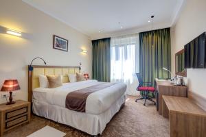 a hotel room with a large bed and a desk at Garden Hotel & SPA in Bishkek