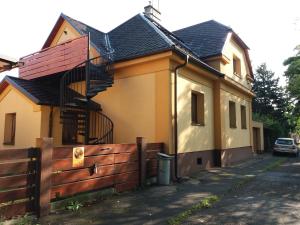 a yellow house with a fence next to it at Apartmány F-M in Frýdek-Místek