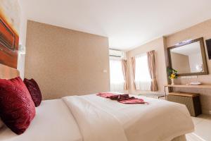 una camera da letto con un letto bianco con cuscini rossi e uno specchio di Roseate Chiang Mai a Chiang Mai