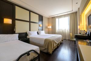 a hotel room with two beds and a window at Hotel Maydrit Airport in Madrid