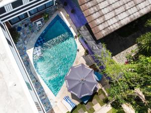 an overhead view of a swimming pool with an umbrella at Vande Guest House in Canggu