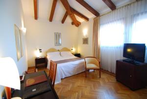 a bedroom with a bed and a television in it at Alla Rocca Hotel Conference & Restaurant in Bazzano