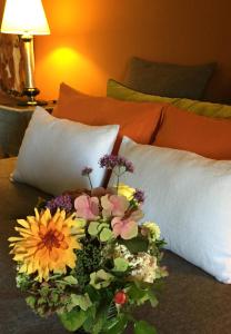 a bouquet of flowers on a bed with pillows at L'école des garçons in Maigné