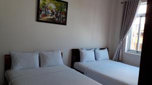 Lotus Apartment Hotel في فنغ تاو: سريرين في غرفة ذات أغطية بيضاء ونافذة