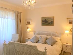 a bedroom with a white bed with two lamps and a chandelier at Carnaby Lodge in Dingwall