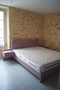 un lit dans une chambre avec un mur de briques dans l'établissement Les Remparts de Sarlat, à Sarlat-la-Canéda