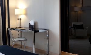 a desk in a room with a chair and a lamp at Hotel Maydrit Airport in Madrid