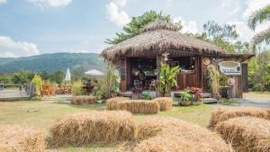 une petite cabane avec des balles de foin devant elle dans l'établissement Phuruarounmai Organic Living Resort, à Loei
