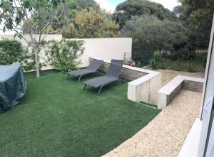 a backyard with two chairs and a table and grass at Les Jasmins in Sainte-Maxime