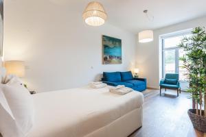 - une chambre avec un grand lit blanc et un canapé bleu dans l'établissement FLH Restauradores Modern Studios, à Lisbonne