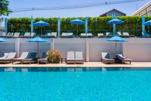 una piscina con sillas y sombrillas azules en Blue Tara Hotel Krabi Ao Nang en Ao Nang Beach