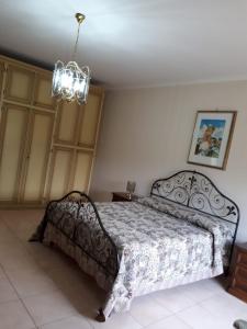 1 dormitorio con cama y lámpara de araña en B&B Porta del Gargano, en San Marco in Lamis