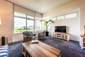 ein Wohnzimmer mit einem Tisch und einem TV in der Unterkunft Waiheke Waterfront Lodge in Oneroa