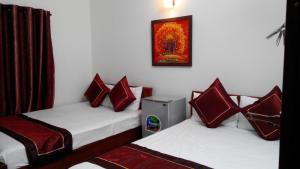 two beds in a room with red pillows on them at Kara Beachside Guesthouse in Da Nang