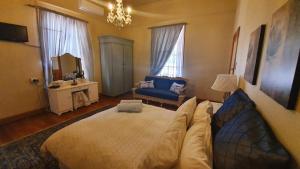 ein Schlafzimmer mit einem großen Bett und einem blauen Sofa in der Unterkunft The Old Watchmakers Guest House in Bethulie