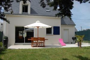 a table and chairs under an umbrella in a yard at La Maison Bleue à 40m de la plage in La Turballe