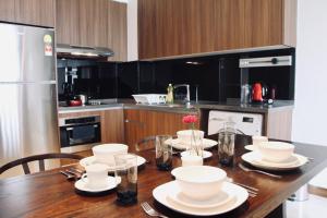 a kitchen with a wooden table with white dishes on it at Damai 88 by Moka near KLCC in Kuala Lumpur