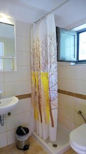 a bathroom with a shower curtain with trees on it at Lion-Suites in Kalyves