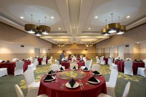 un hombre de pie en un salón de banquetes con mesas y sillas en KHAS Pekanbaru Hotel en Pekanbaru
