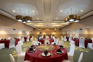 un homme debout dans une salle de banquet avec des tables et des chaises dans l'établissement KHAS Pekanbaru Hotel, à Pekanbaru