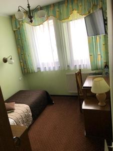 a bedroom with a bed and a desk and windows at Hotel Restauracja Podzamcze in Szczecin