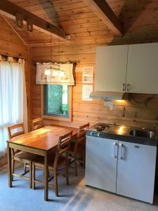 uma cozinha com uma mesa de madeira, uma mesa e um fogão em Mandalselva Laksehytter em Marnardal