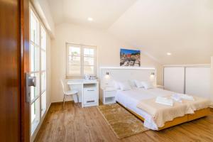 a white bedroom with a bed and a desk at Idassa Atrium rooms in Zadar